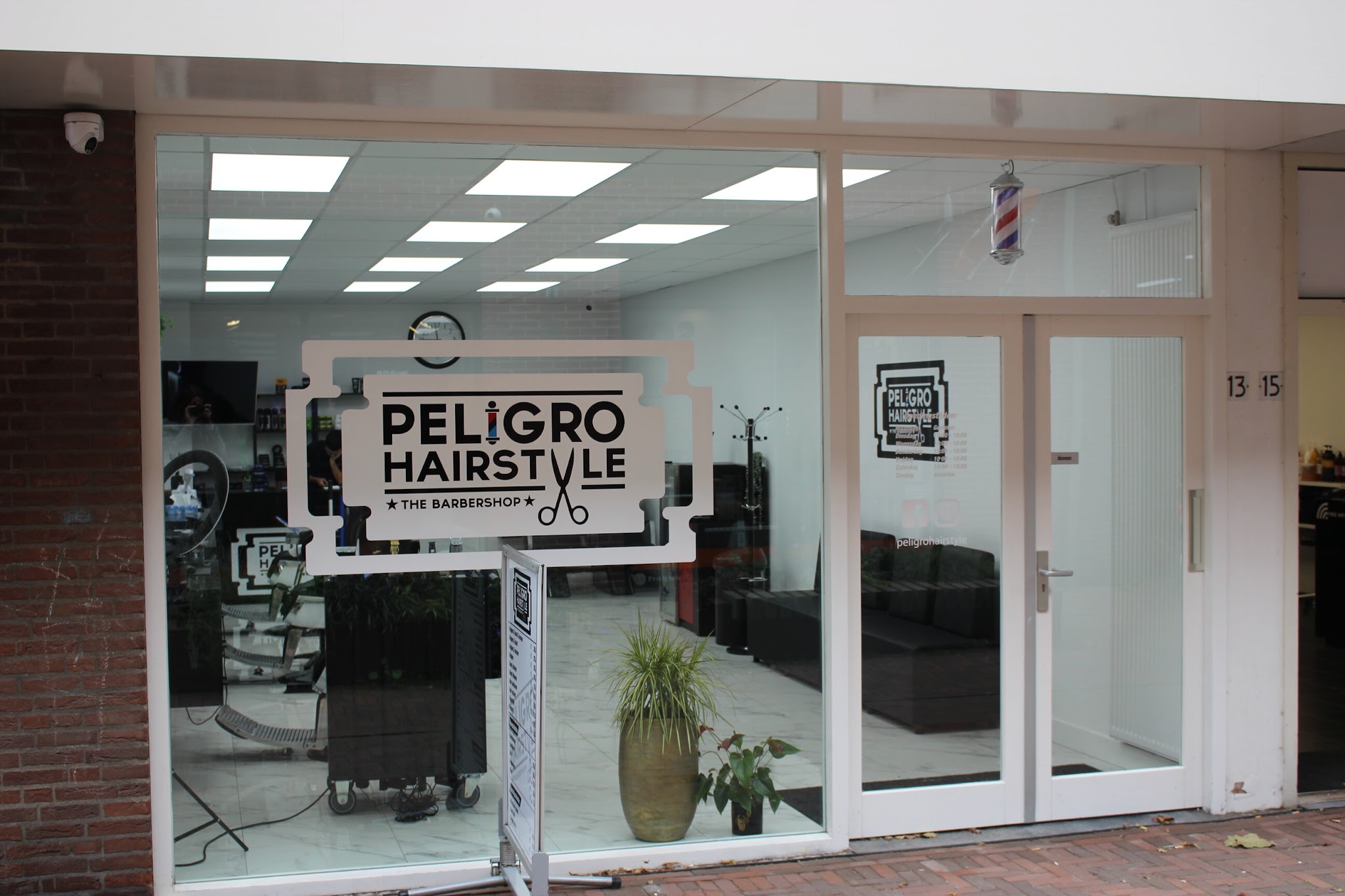 De winkelpui van Meerstraat 13 met het Peligro Hairstyle-bord achter het raam